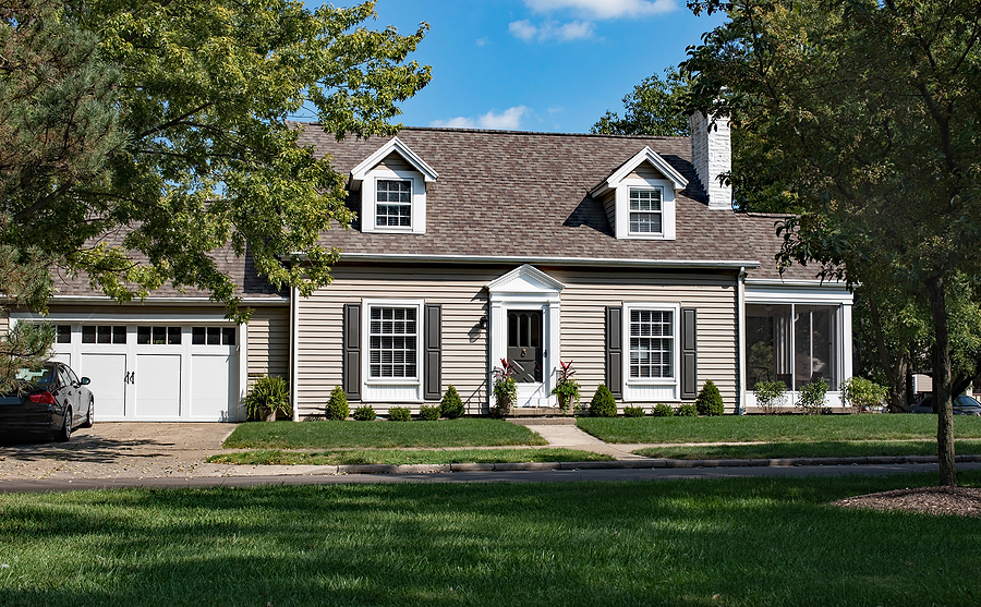 A suburban home with beige siding and white trim, highlighting the work of professional siding installers.